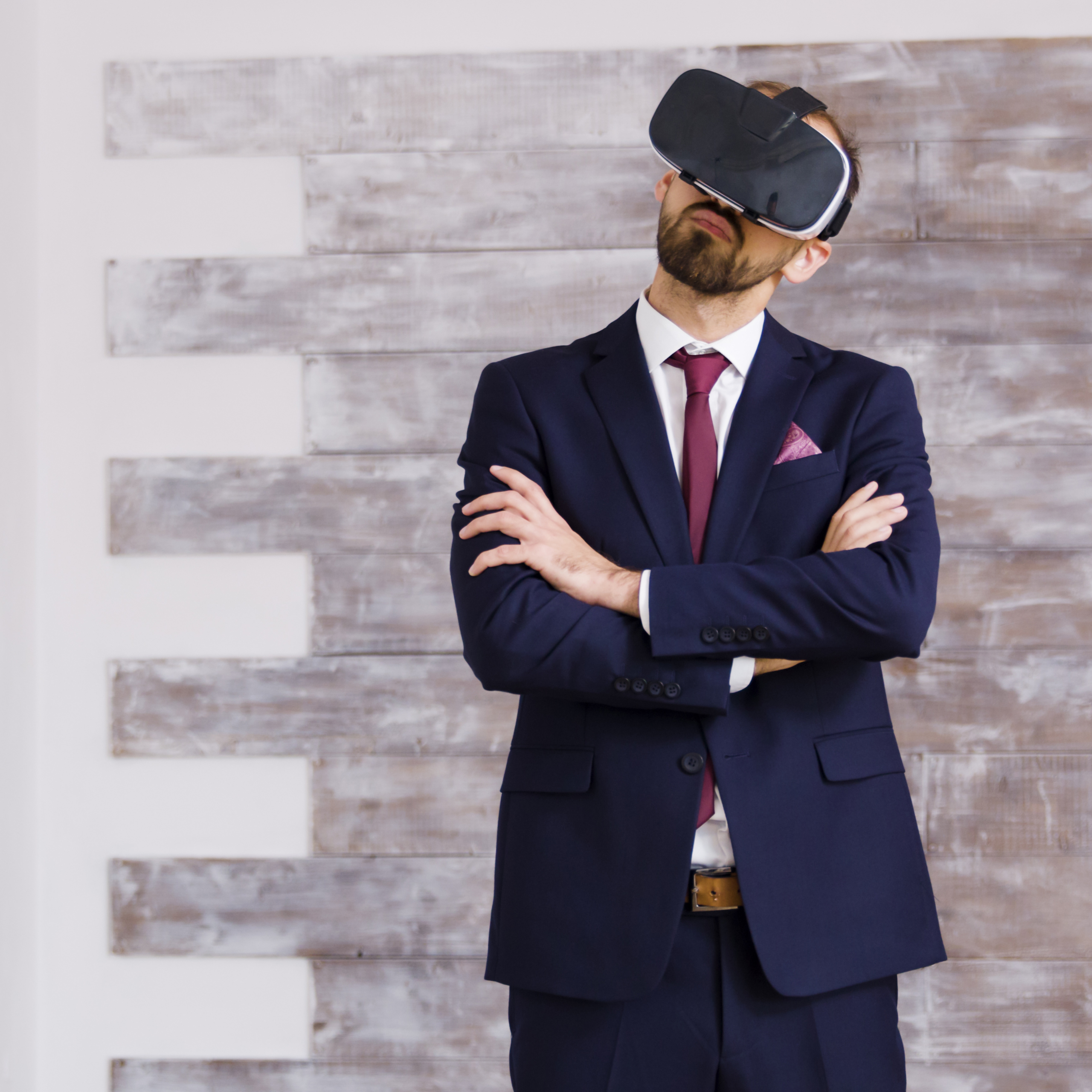 Homem de terno usando óculos de realidade virtual com os braços cruzados.