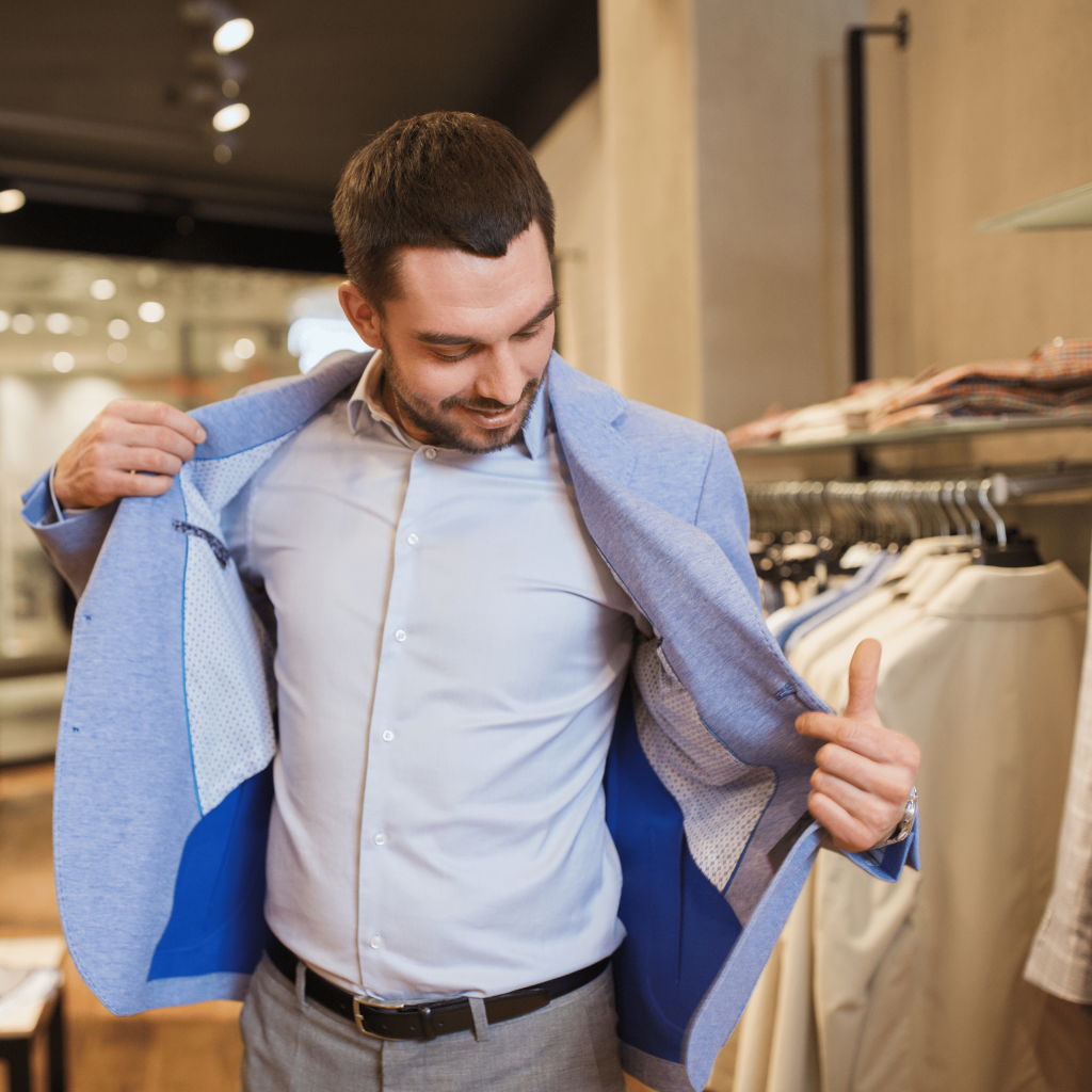 Homem experimentando blazer azul em loja de roupas masculinas.